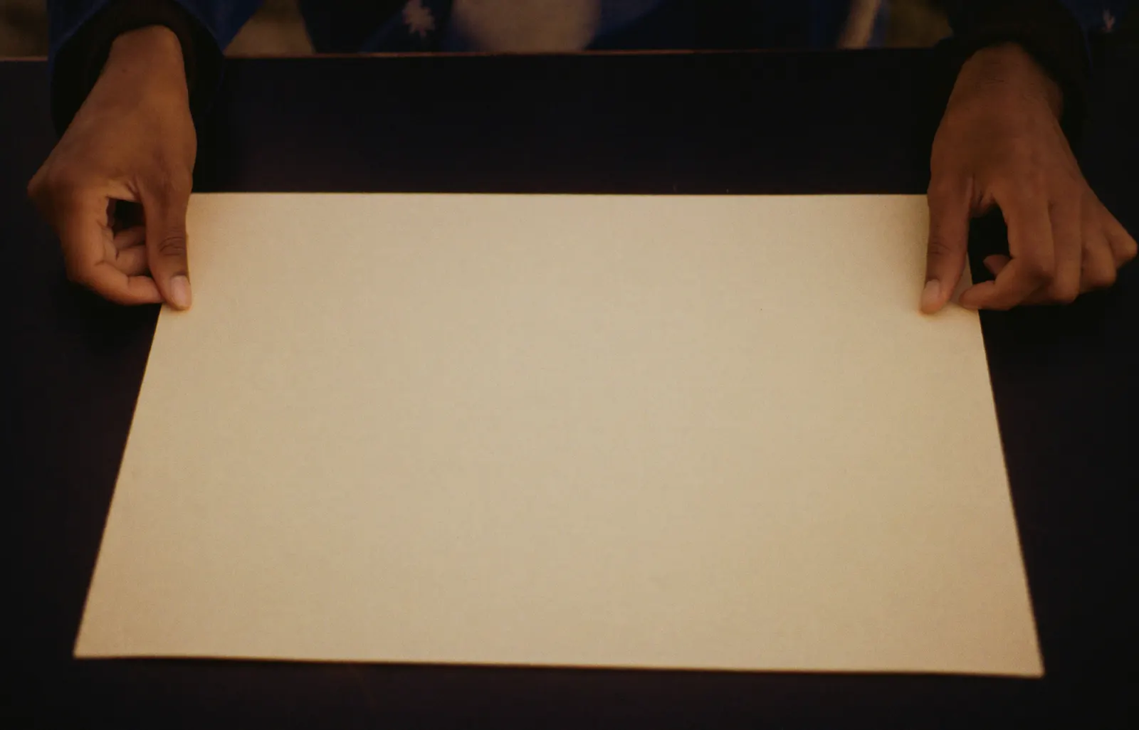 A finished form resting on a desk beside a pair of hands