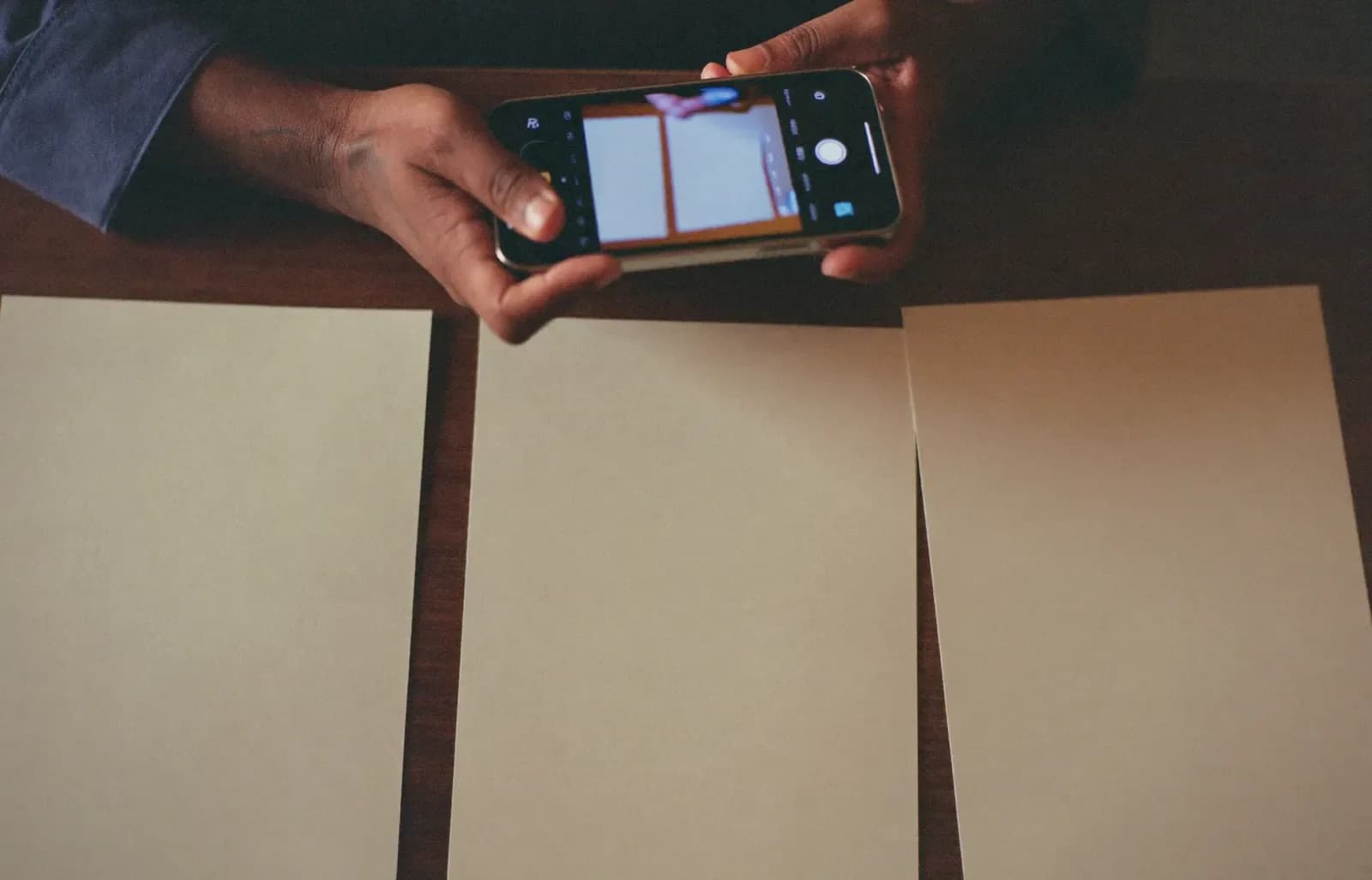 Hands photographing documents laid out on a table with a phone